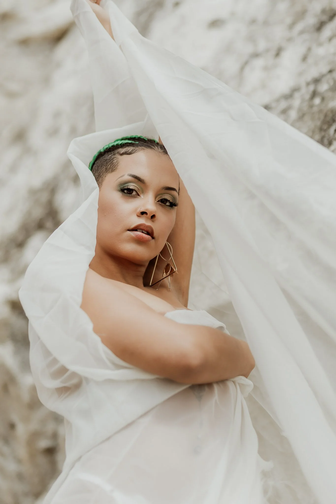 Person posing with white sheer fabric outdoors.