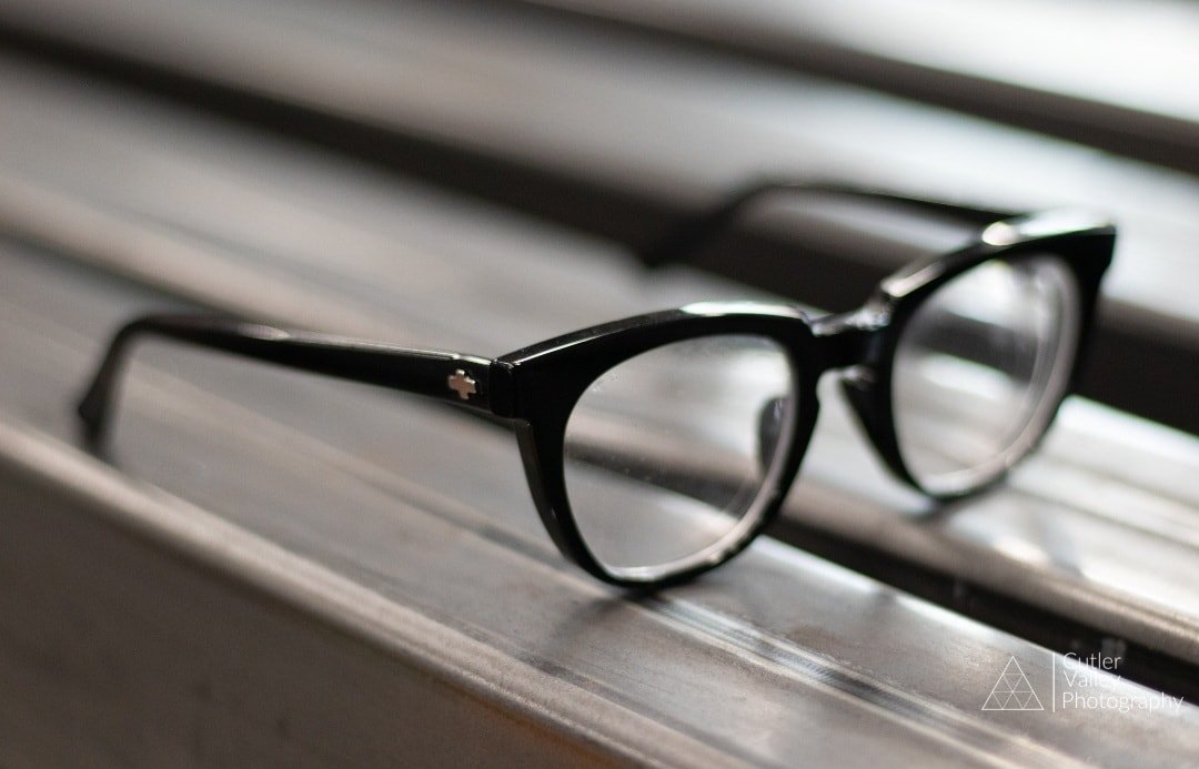 Black eyeglasses resting on a wooden bench.