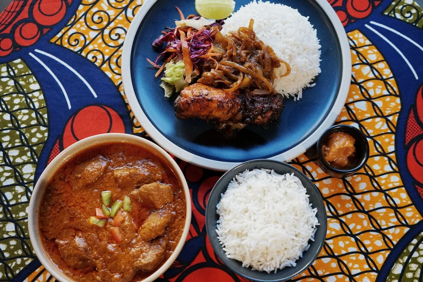 Overhead view of shared dishes of stew and rice on a patterned tablecloth
