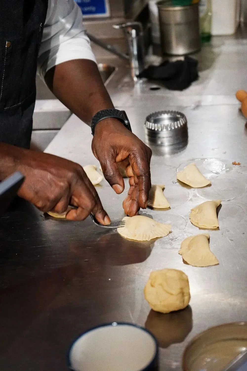 Hands folding dumplings at a team cooking activity.