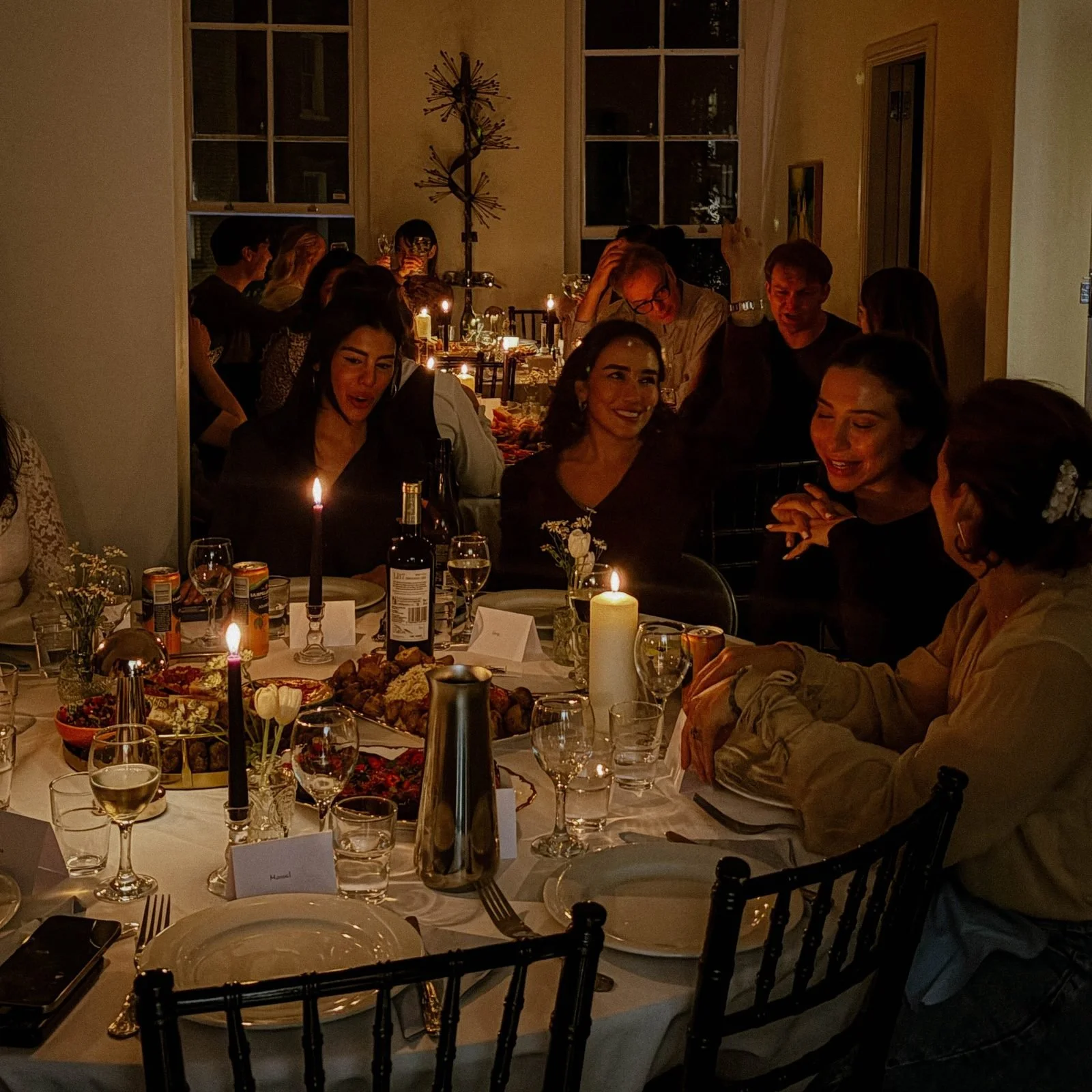 Guests gathered around a candlelit table at an intimate supper club dinner