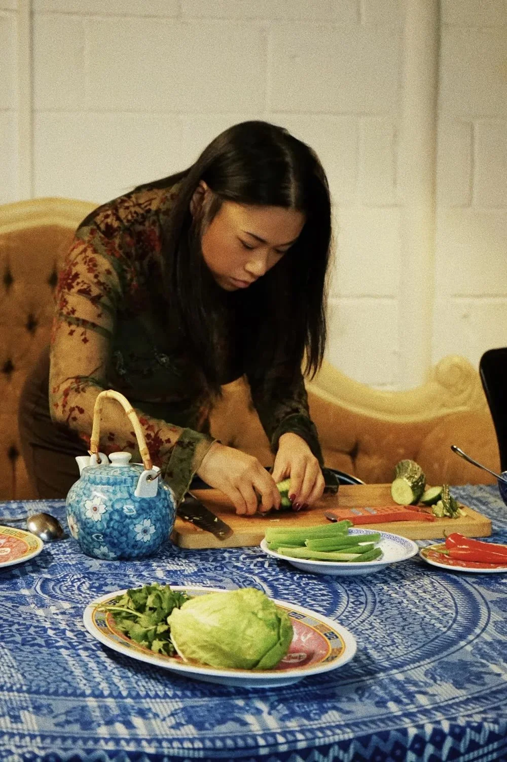 Chopping vegetables beside a teapot at a cooking workshop.