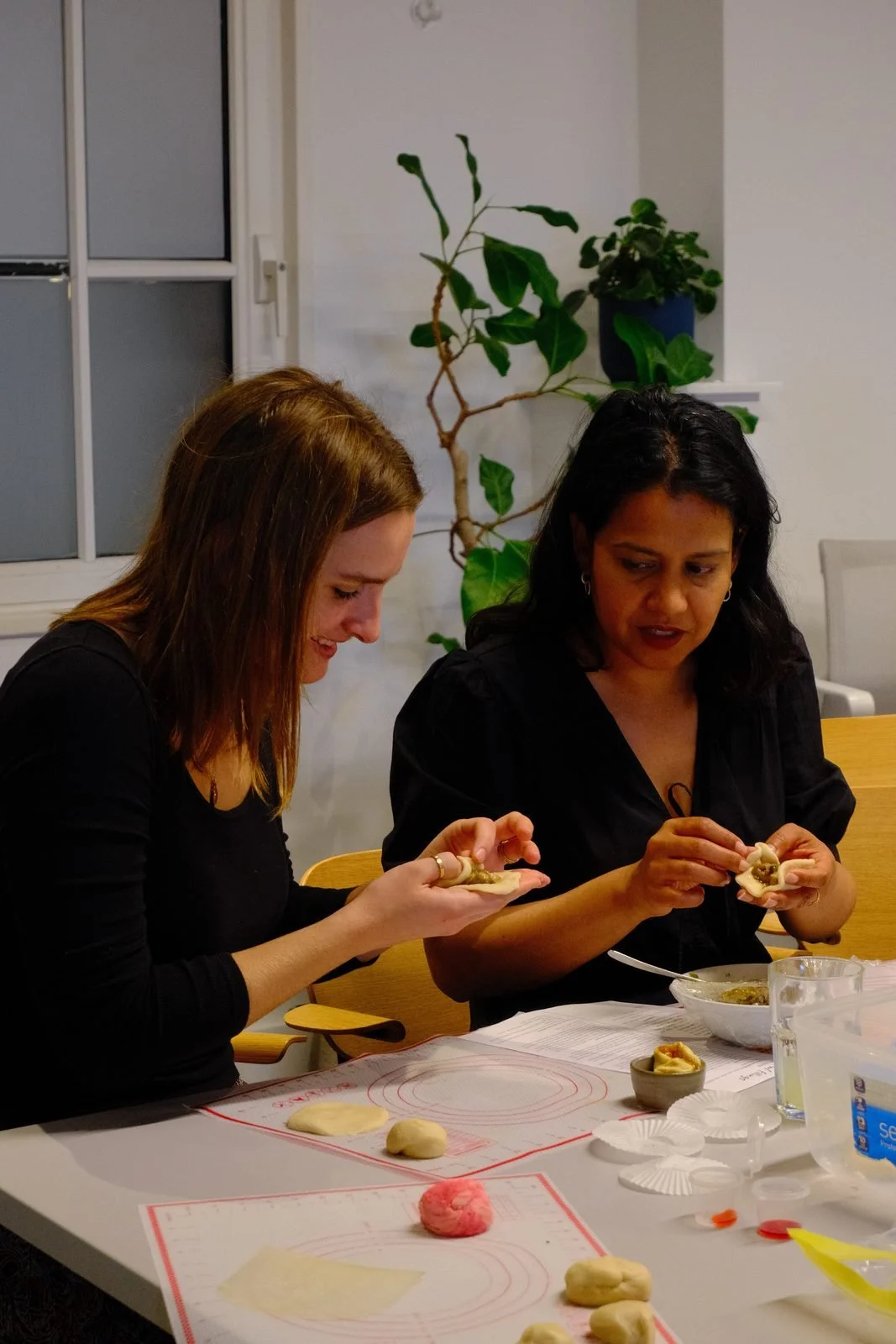 Two people folding filled dumplings at a hands-on team cooking workshop