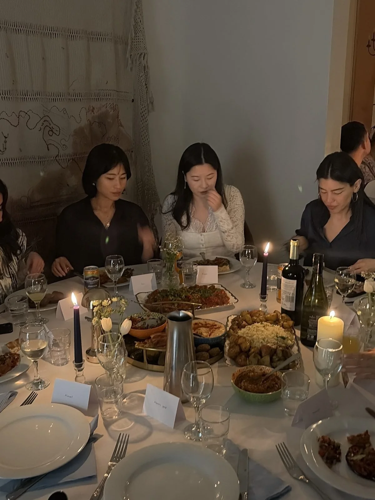 Guests sharing a candlelit table laden with dishes at a private dinner party