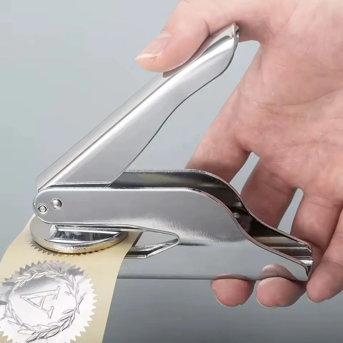 Persona apretando una pistola de pegatinas doradas con un sello en forma de A en una etiqueta.