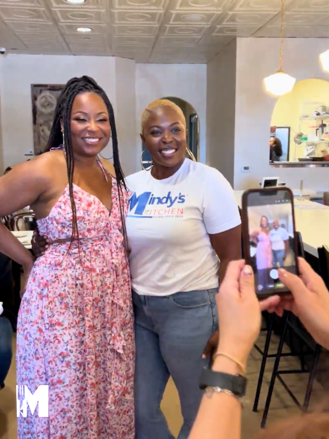 A photo being taken on a phone of two ladies posing in front of camera