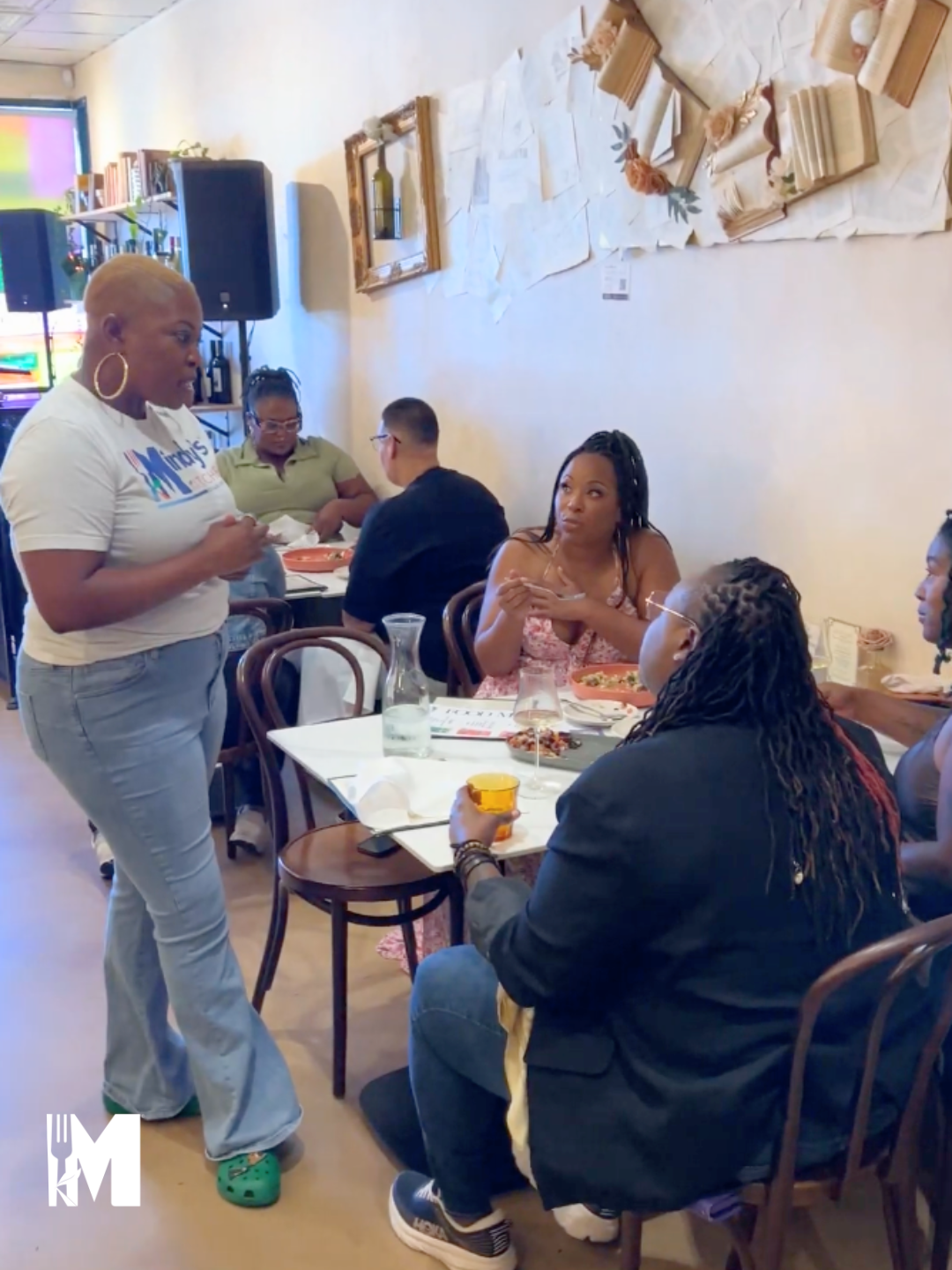 Server interacting with guests at a table with food and wine glasses