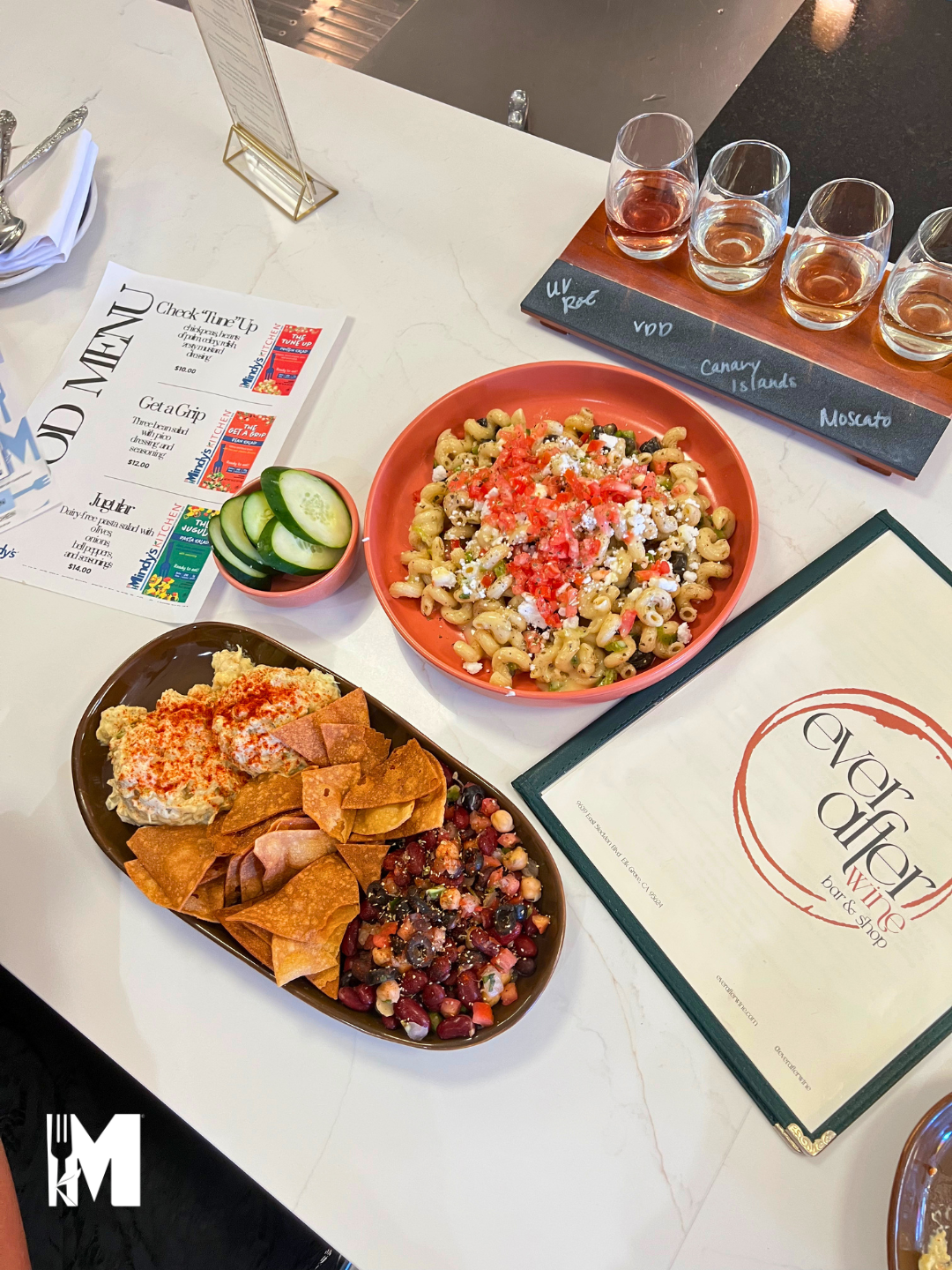 Table shot of the pasta, bean and chickpea salad on a plate with menus on the side