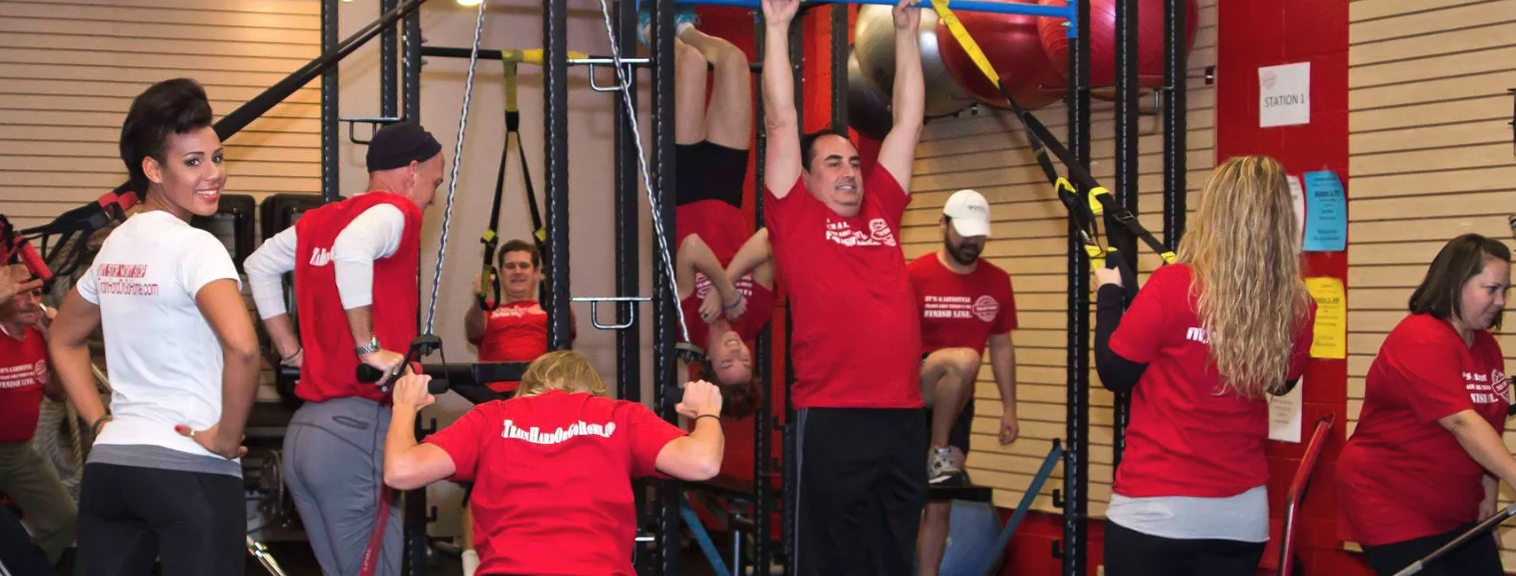 Action Fitness members and trainers participating in a group workout using suspension and strength-training equipment