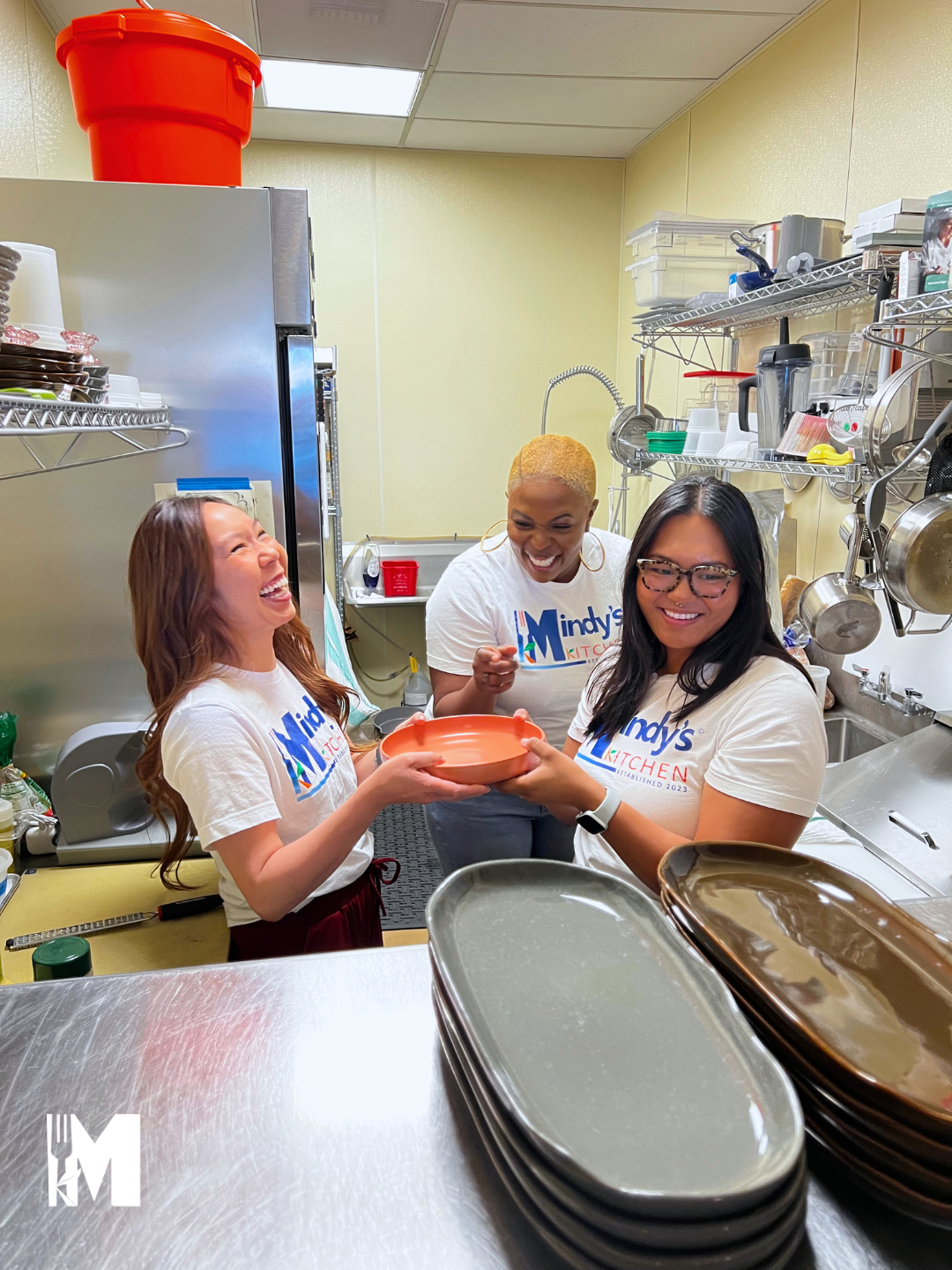 Three ladies holding one salad plate with laughter on their faces