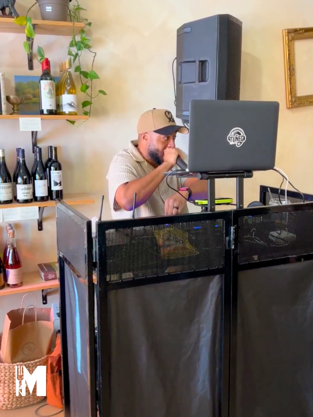 Dj is holding a mic in his hand, sitting behind his music station