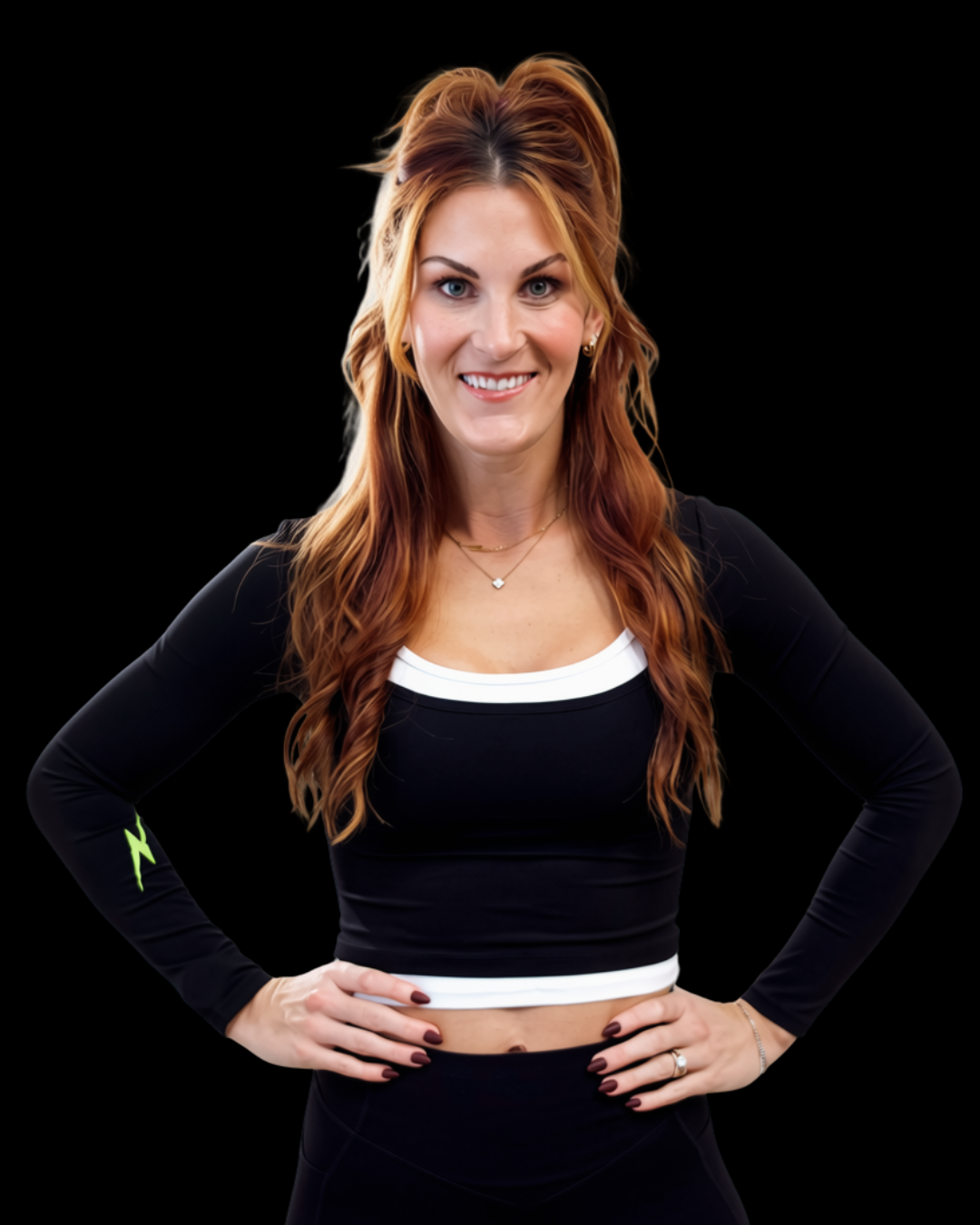 A woman with long, wavy red hair, smiling, wearing a black sports crop top with white trim and matching black leggings, standing with hands on hips, against a black background.