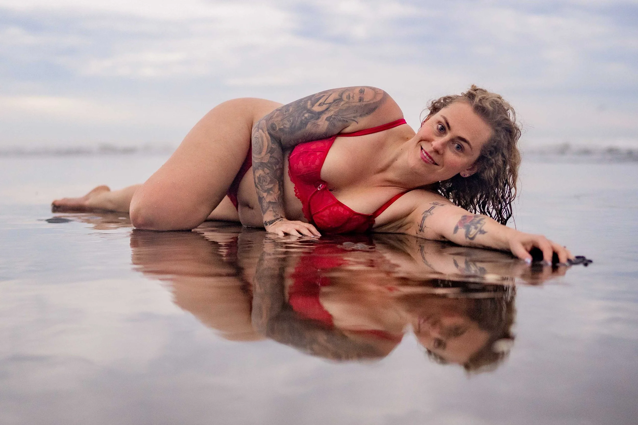 lady in red lingerie lying on the beach during her empowerment and boudoir photoshoot in auckland Franklin area