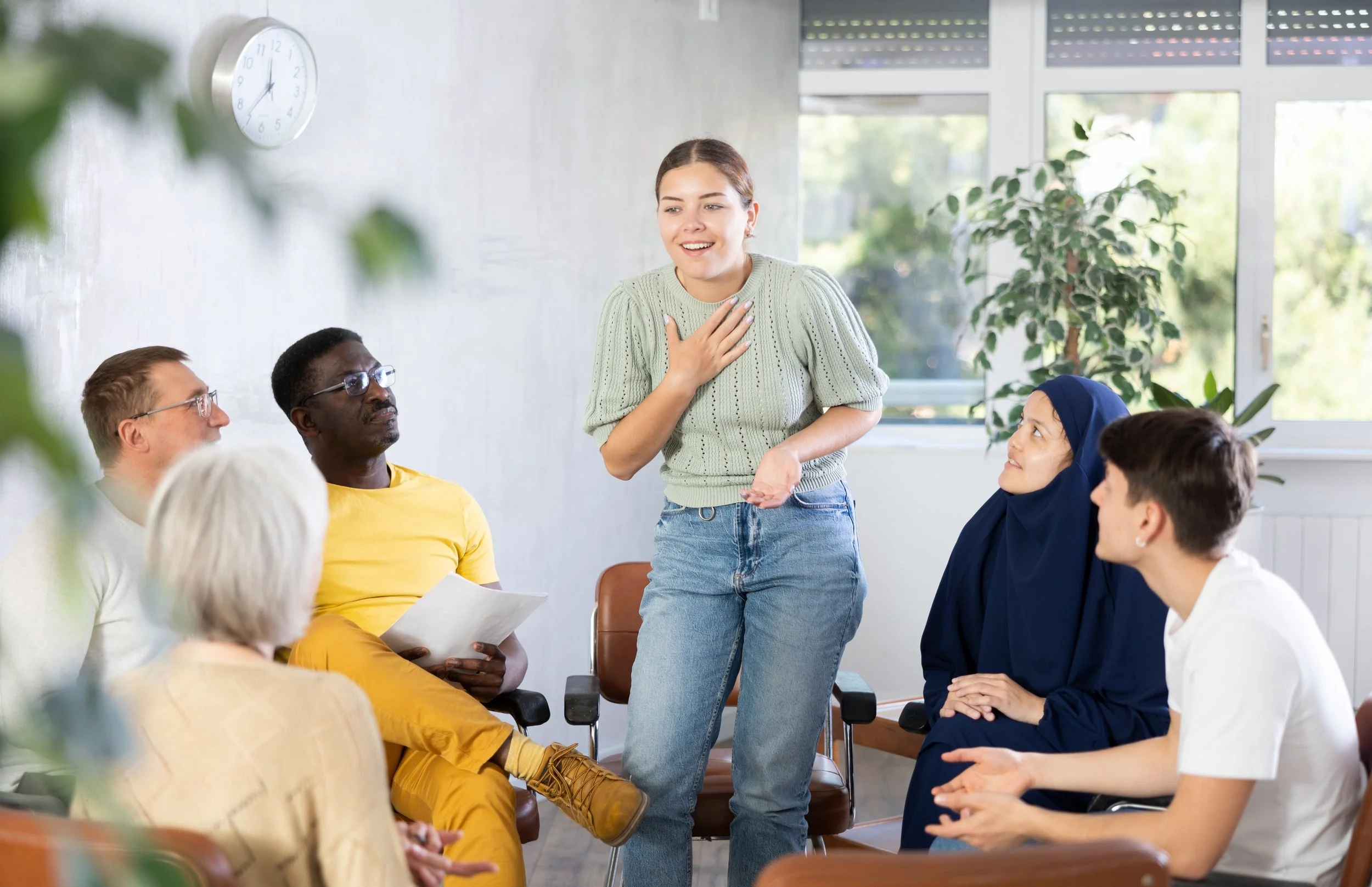 A group of people seated in a circle listening as one participant speaks.