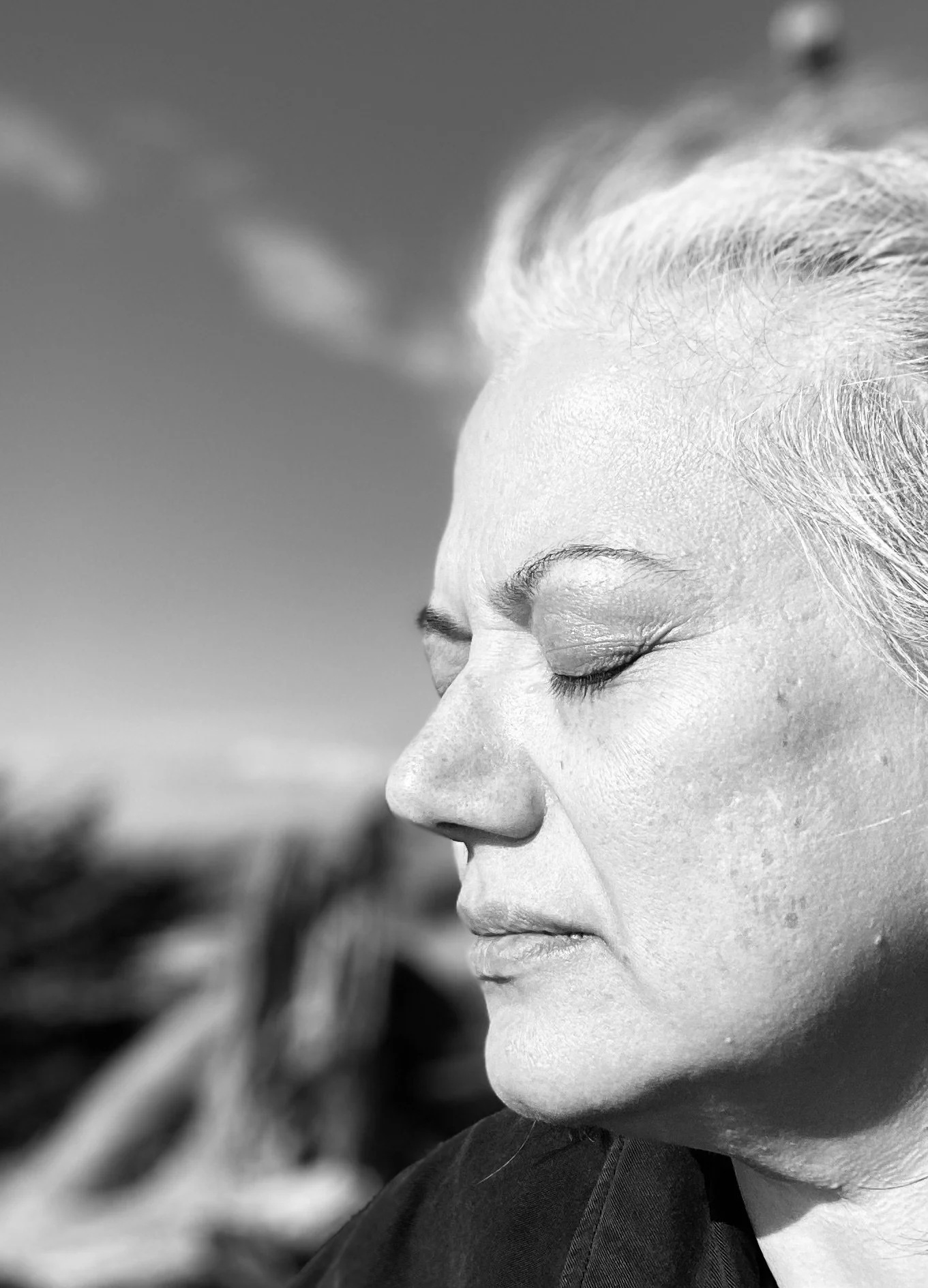 Black-and-white profile portrait of Nidia Trujillo with her eyes closed.