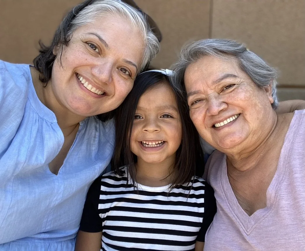 Nidia, her daughter Ellie, and her mother smiling together.