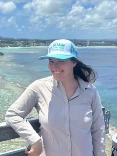 GCRI staff member smiling at the camera with greenery and the ocean in the background