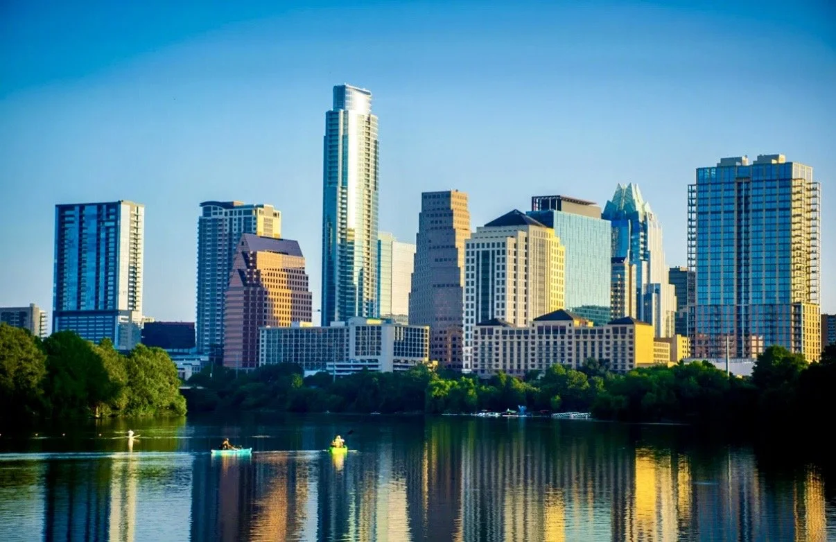 Downtown Austin skyline with modern high-rise buildings and water with kayakers in the foreground.