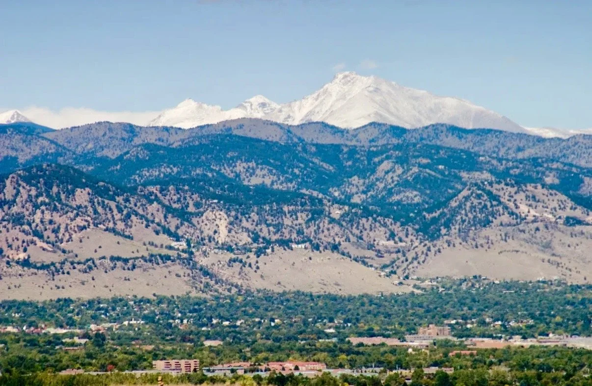 A landscape of snow-capped mountains in the background with Boulder, Colorado in the foreground.