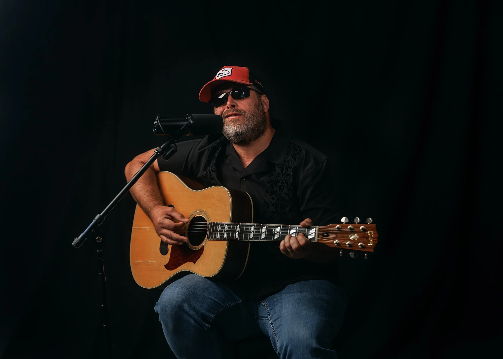 Studio branding photograph of musician singing while playing guitar
