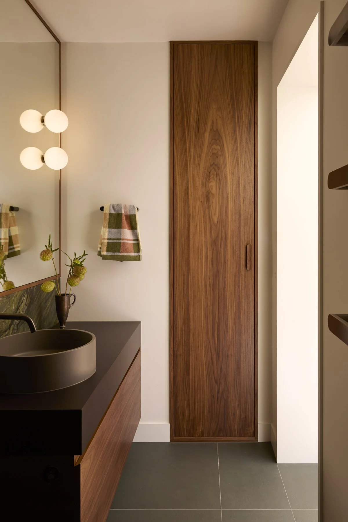 Bathroom walnut tall built-in cabinet vanity with black porcelain top and lights installed on a mirror