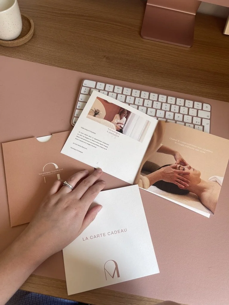 Cartes de cadeau, un clavier blanc, une tasse blanche, un support ordinateur rose sur un bureau en bois.