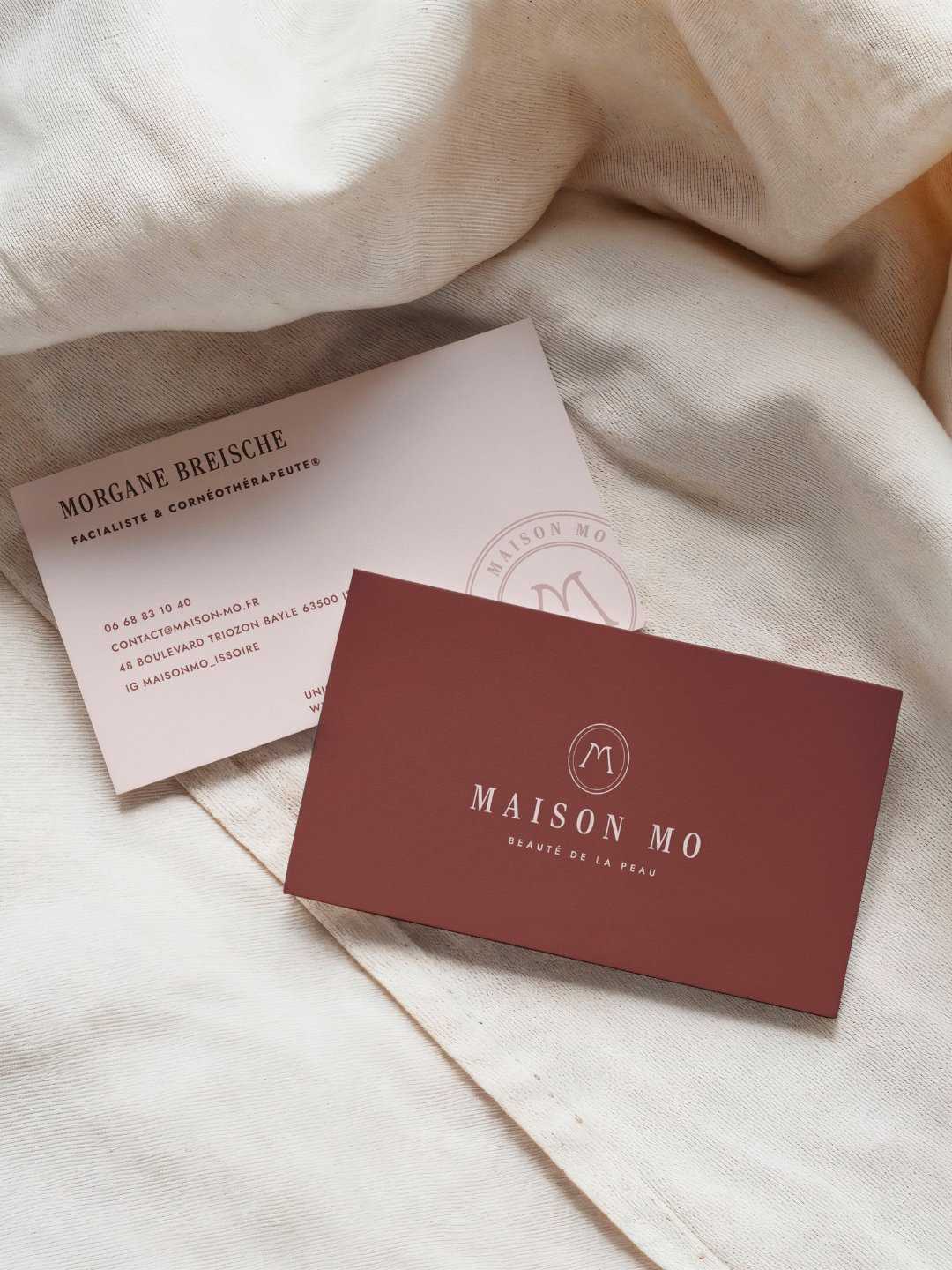 Cartes de visite pour Maison Mo, une marque de beauté de la peau, déposées sur un tissu beige.