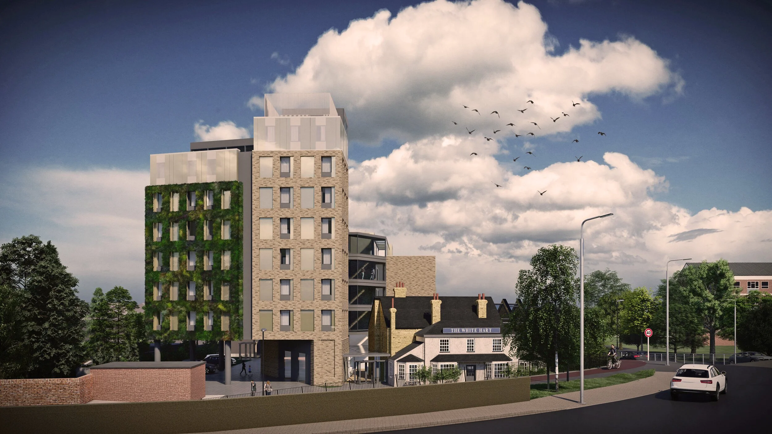 A modern multi-story building with green vertical gardens on its facade, situated in a neighborhood with older houses, trees, parked cars, a cyclist, and a cloudy sky with birds flying overhead.