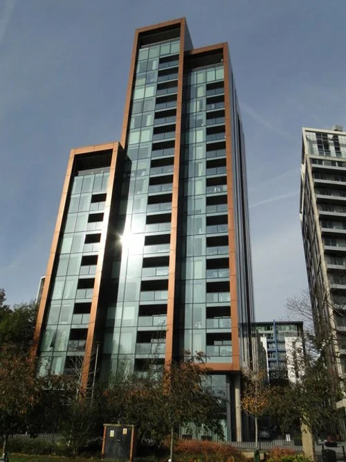Modern glass and brick high-rise apartment building under a clear blue sky.