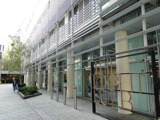 Modern commercial building with glass windows, metal accents, and a business sign reading "CUB" outside.