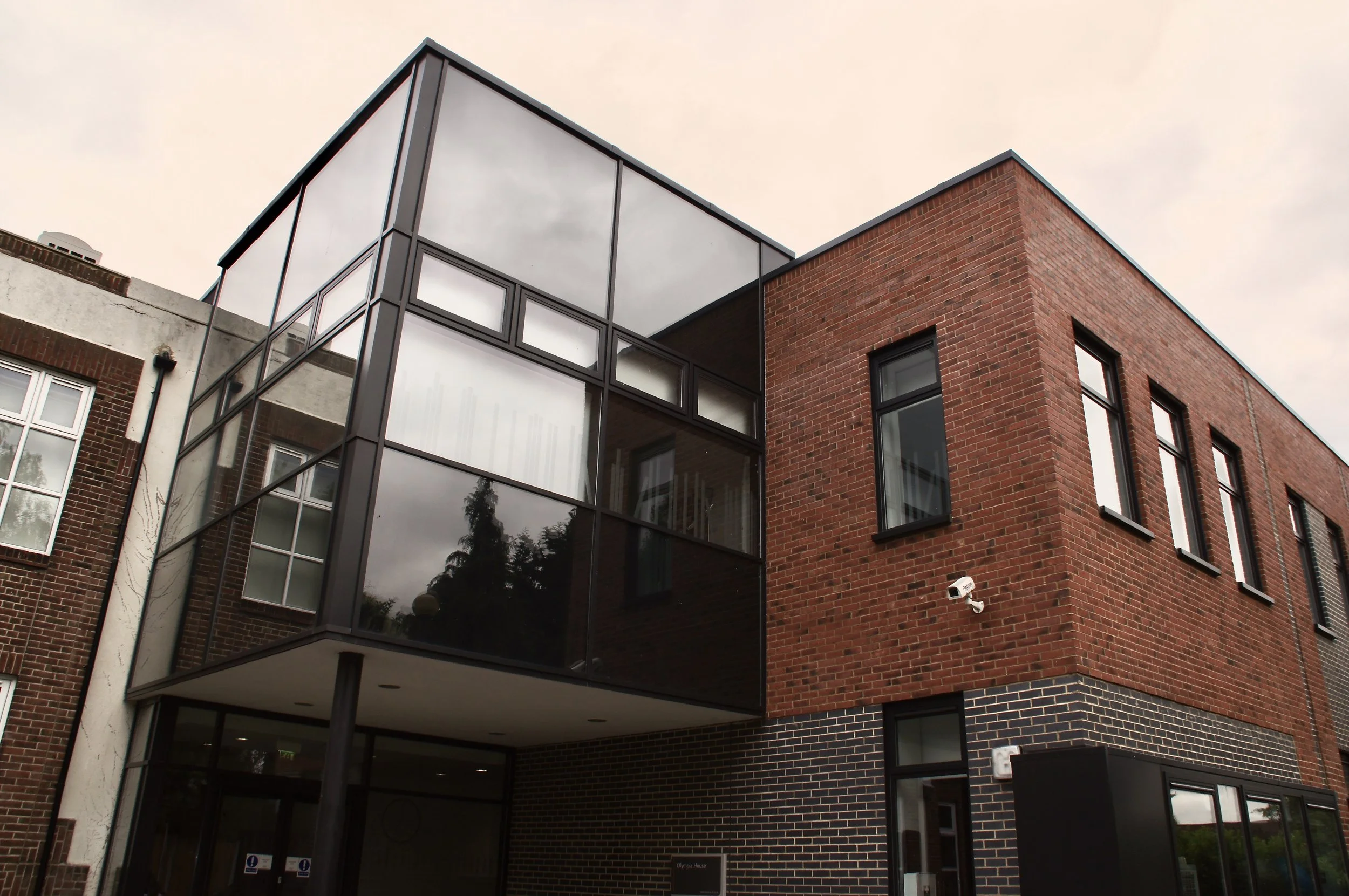 Modern building with red brick and dark brick lower section, featuring large glass windows