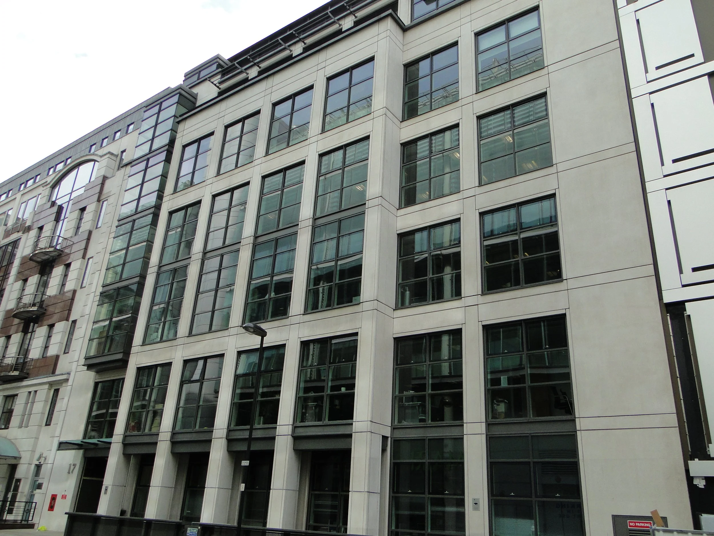 Modern multi-story office building with large glass windows and a light-colored facade.