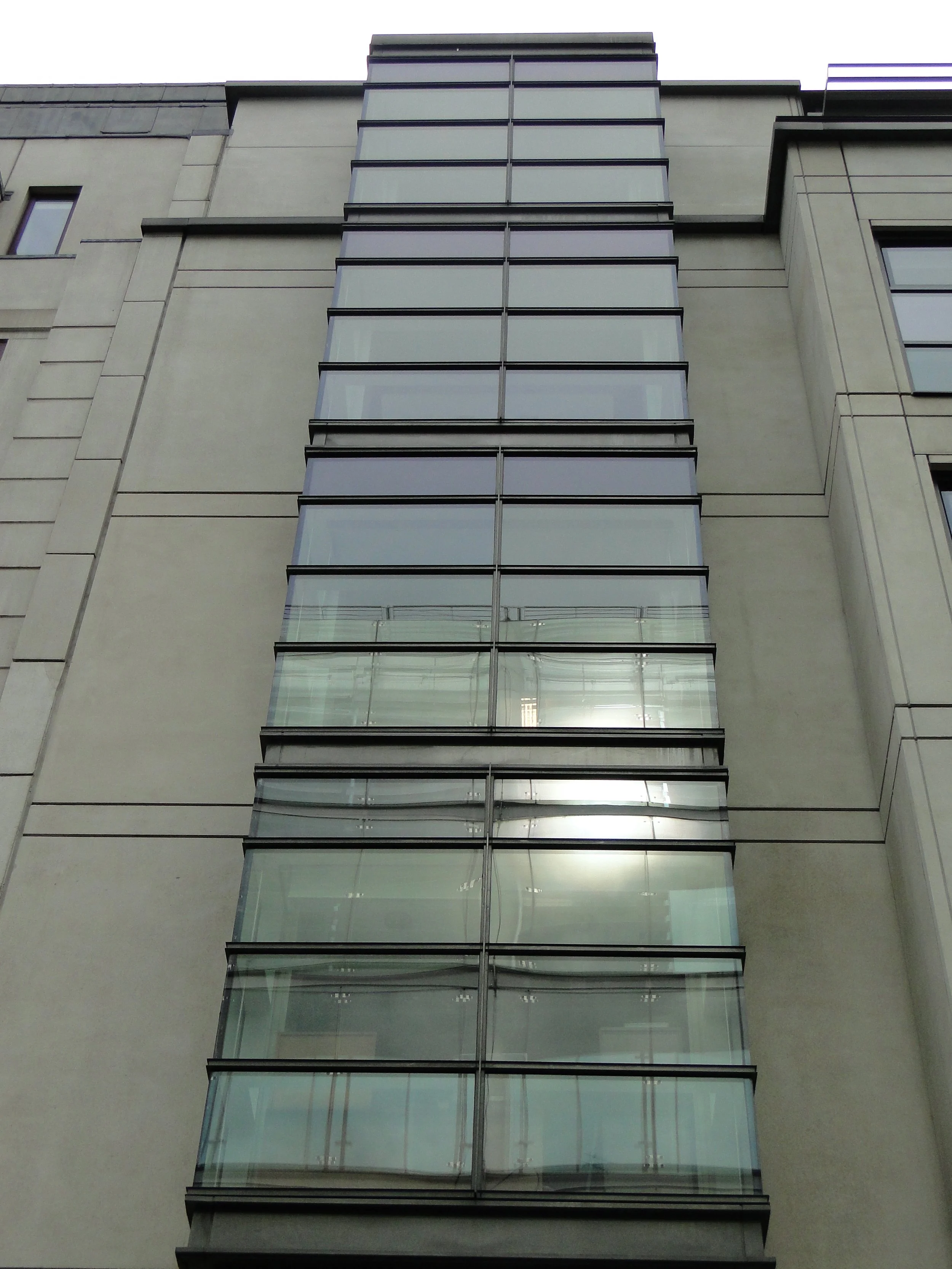Tall modern building with glass balcony railings on each floor.