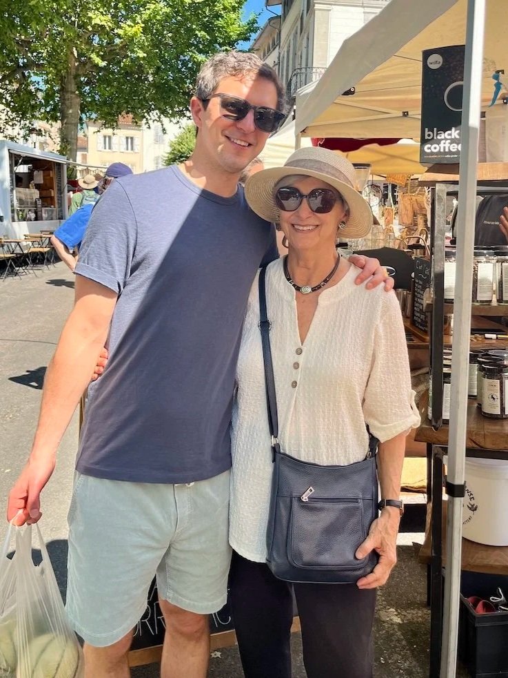 Young man standing with arm around shoulder of woman while standing in outdoor market.