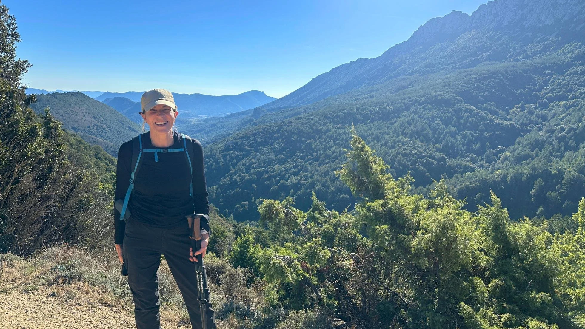 Middle aged female hiker smiling on a sunny day with mountains in the background