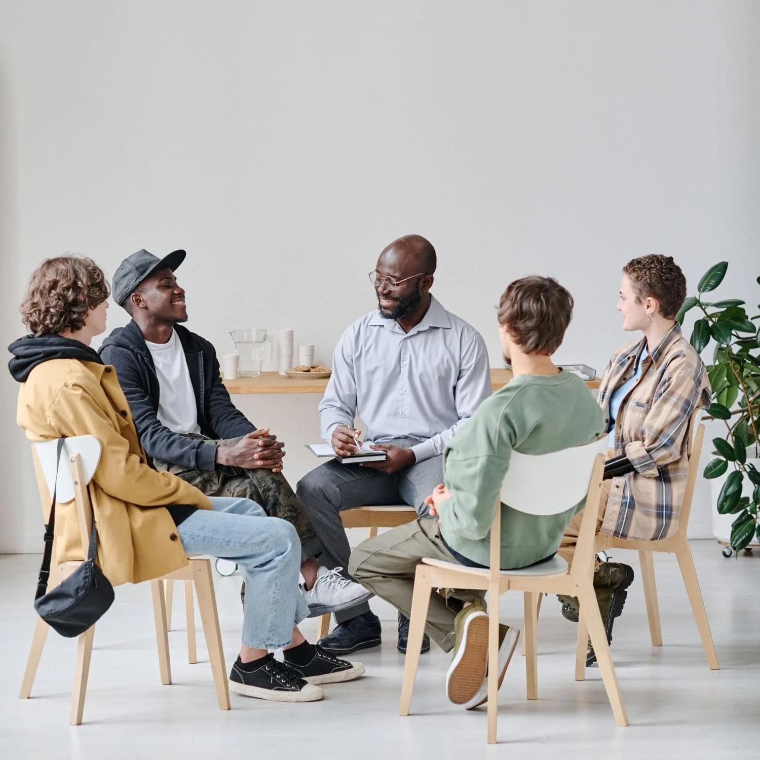 Group of 5 individuals sitting in a circle at coaching event