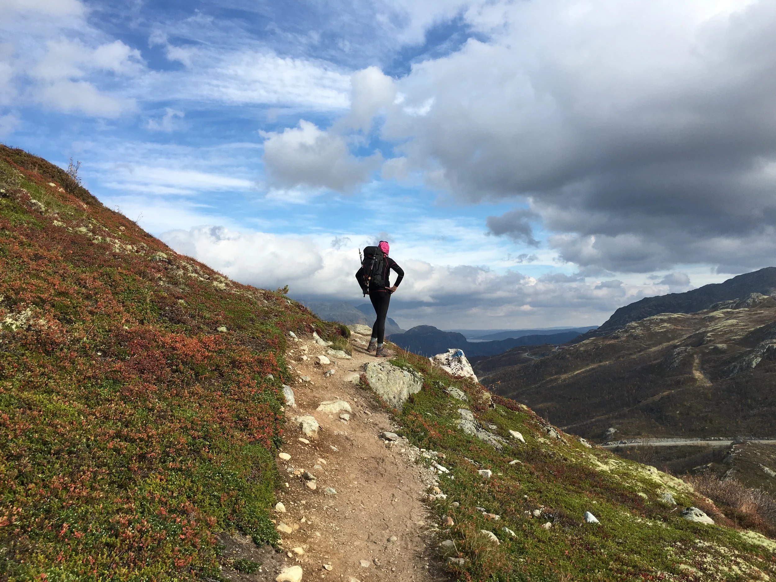 Woman standing with hands on hips on a hiking trail in Norway.