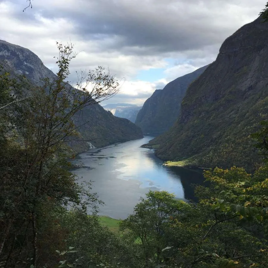 Fjord with deep blue waters and a cloudy sky.