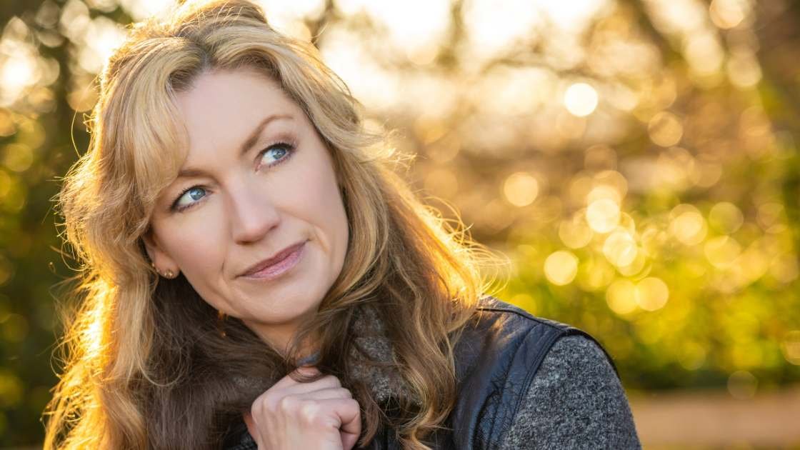 Midlife woman in her 50s thinking while sitting outside.