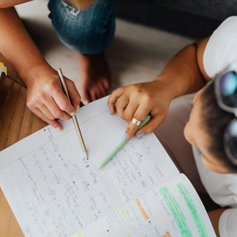 Student and tutor sitting around math notebook.