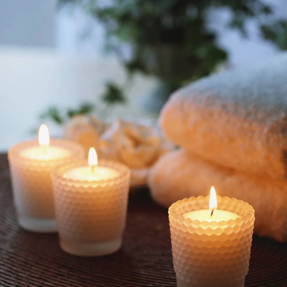 Three lit candles with white towels in the background.