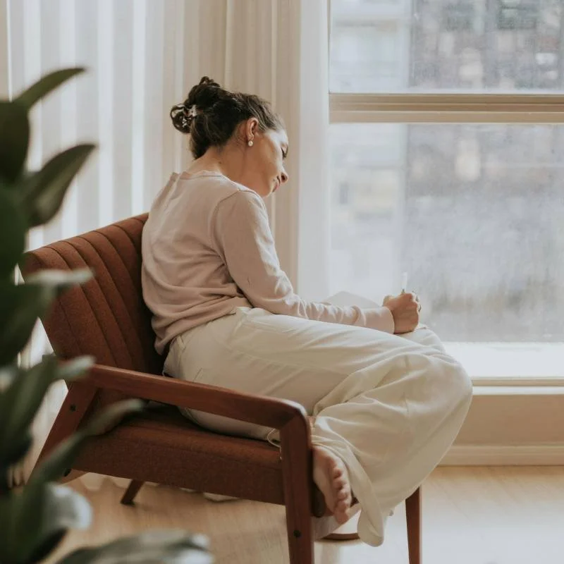 Woman sitting in chair and writing in journal.