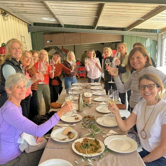 Women at a wine tasting raising their glasses in a toast.