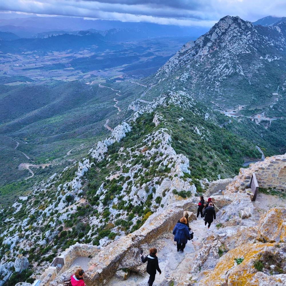 People walking along a stone path on the side of a mountain.