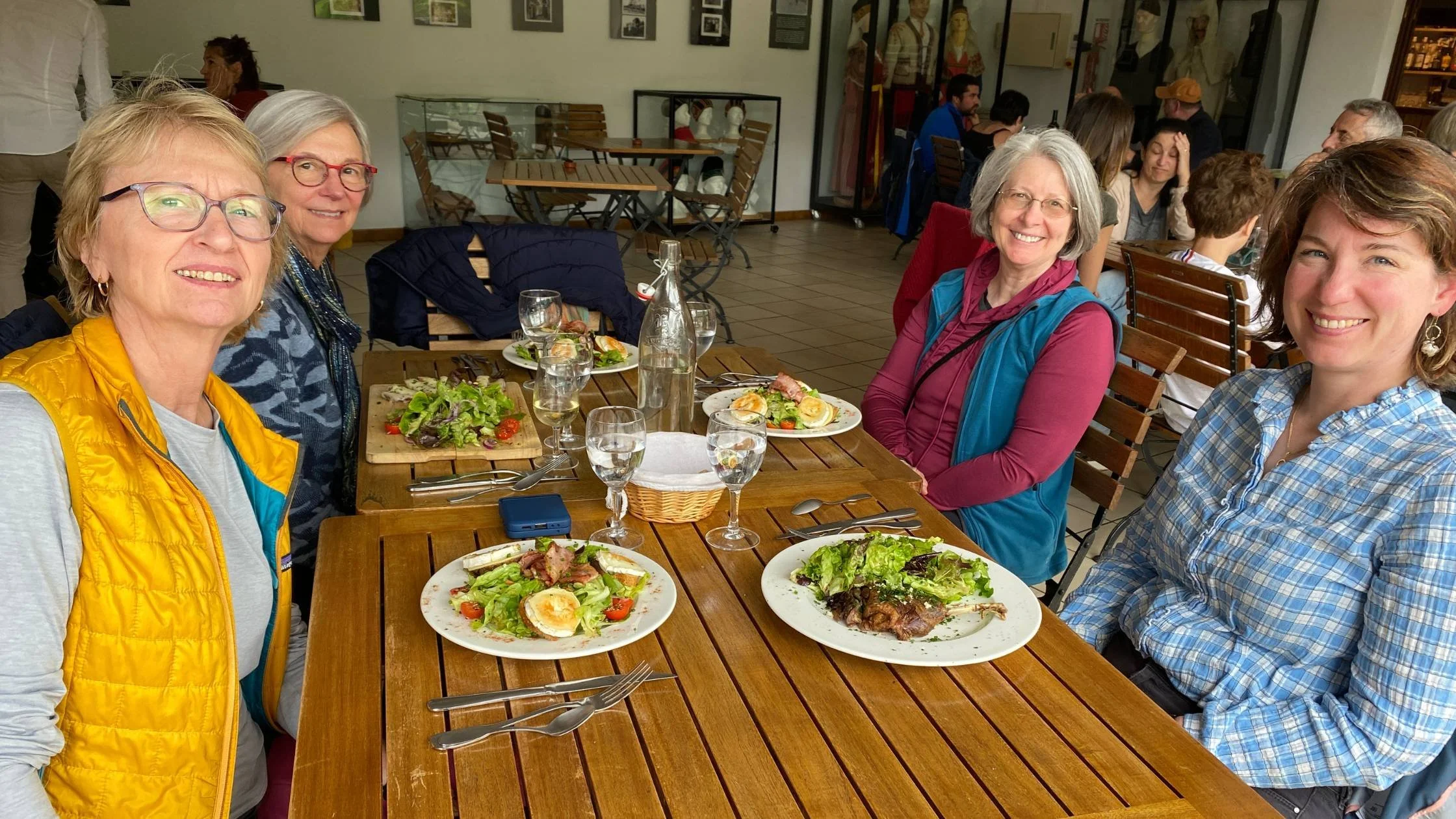 four women eating salad and smiling at the camera from Athara trip
