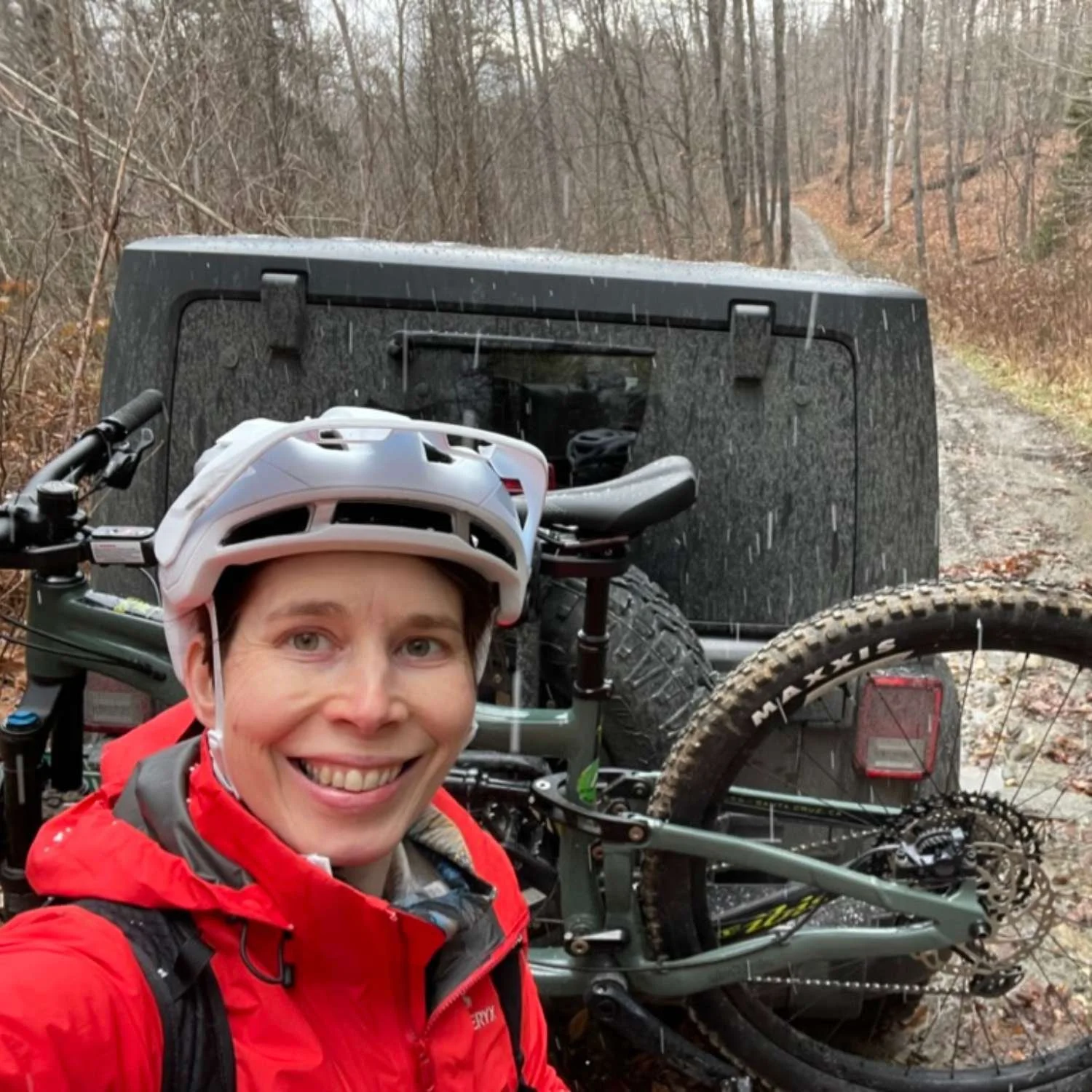 Seoka mountain biking during an Athara retreat in Europe, standing beside her bike on a wooded trail.