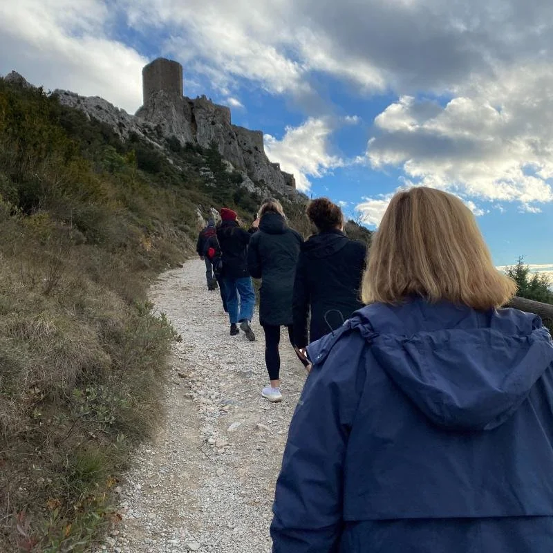 People walking uphill towards Queribus Castle in France.