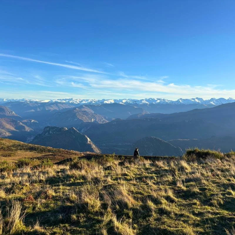 Woman standing alone with snowy Pyrenees Mountains in the background.