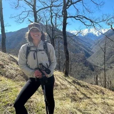 Sarah, co-founder of Athara Adventure, hiking on a mountain trail with trekking poles.