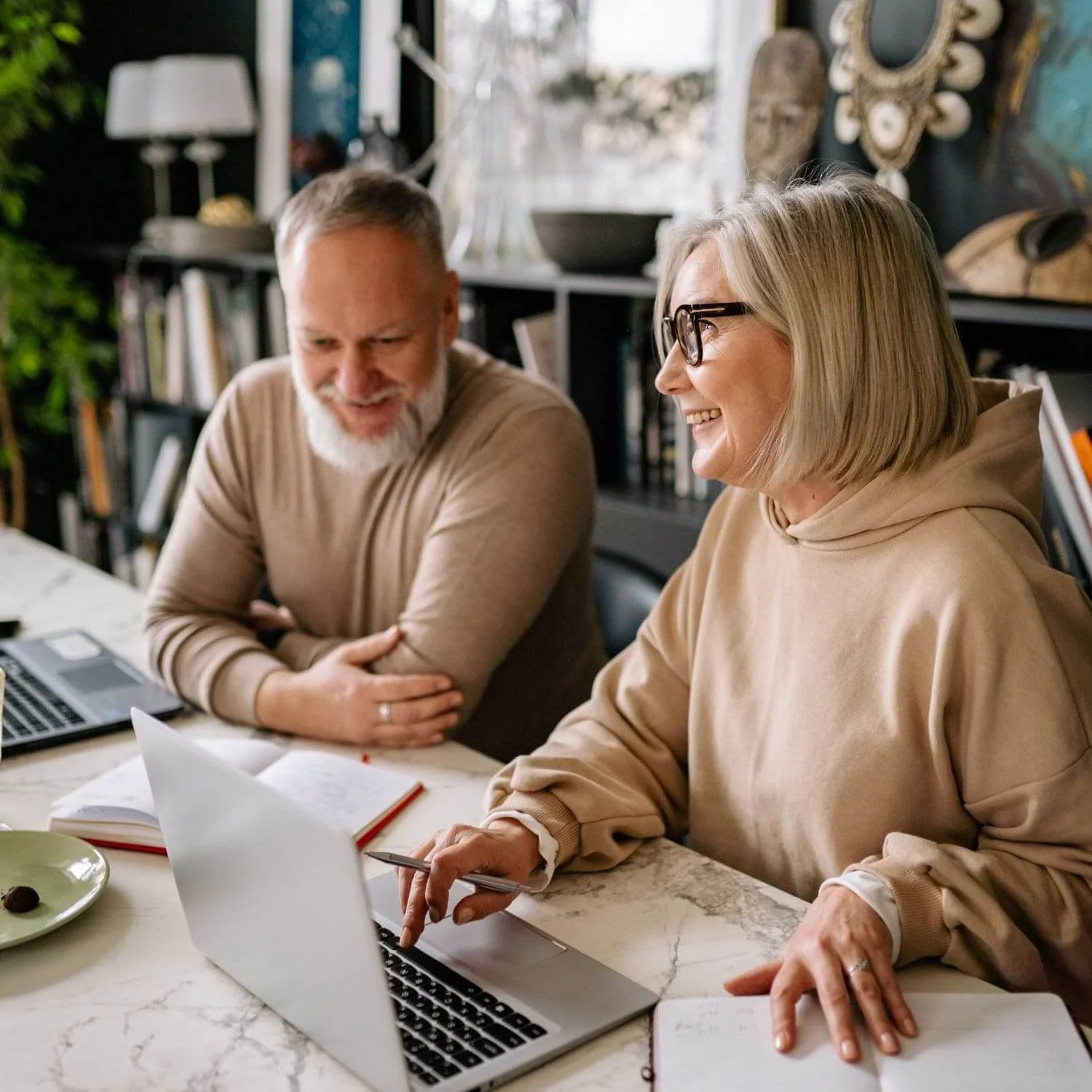 Older man and woman sitting by their laptop tuning in to online coaching event.